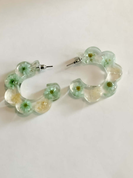 C Shaped Flower EarringsThese C Shaped Daisy encase Flower Earrings will add a touch of elegance to any ensemble. Expertly crafted to feature a beautiful blend of green and white, these earrings will add a subtle, stylish flair to any look.C Shaped Flower